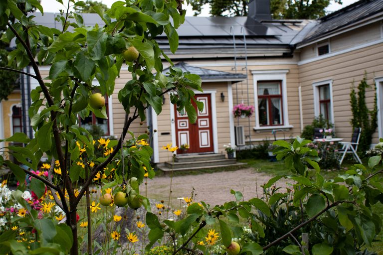 Kukkia ja omenapuita vanhan talon edessä.